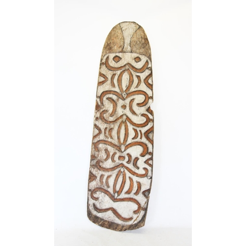 412 - An Asmat shield, Papua New Guinea, carved in relief with tribal motifs upon a white ground, 215cm x ... 