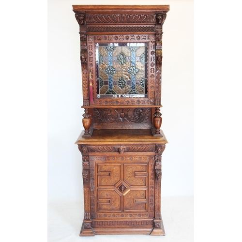 712 - A late 19th century French oak and stained glass cabinet, with a moulded cornice above a carved frie... 