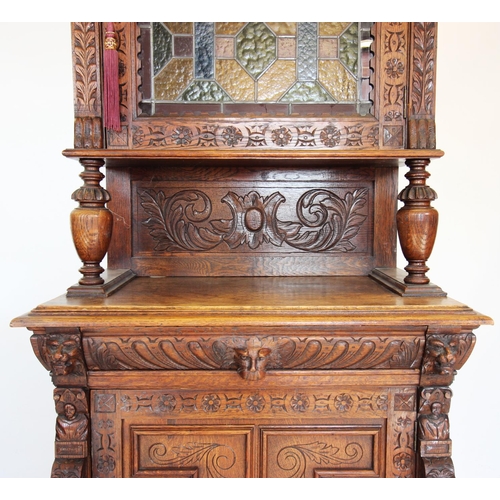 712 - A late 19th century French oak and stained glass cabinet, with a moulded cornice above a carved frie... 