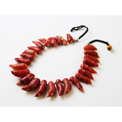 237 - An untested coral coloured necklace, designed as twenty six tapering beads on cord, 57cm long overal... 