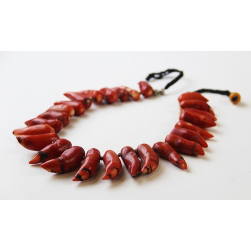 237 - An untested coral coloured necklace, designed as twenty six tapering beads on cord, 57cm long overal... 