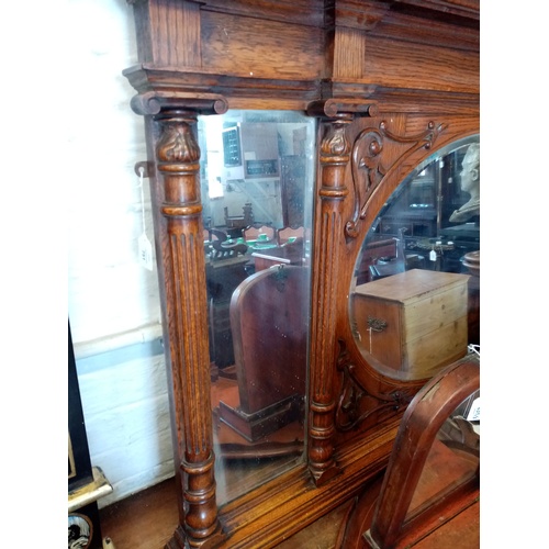 751 - An early 20th century Art Nouveau oak over mantle mirror, the central oval bevelled mirrored plate e... 