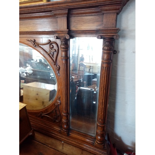 751 - An early 20th century Art Nouveau oak over mantle mirror, the central oval bevelled mirrored plate e... 