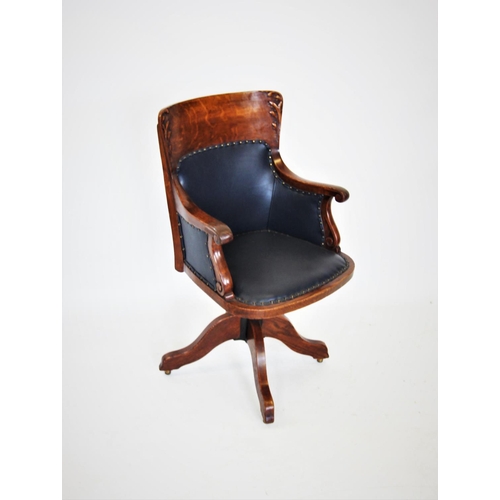 679 - A late 19th century oak adjustable desk chair, the concave back with carved leaf detail, above a pad... 