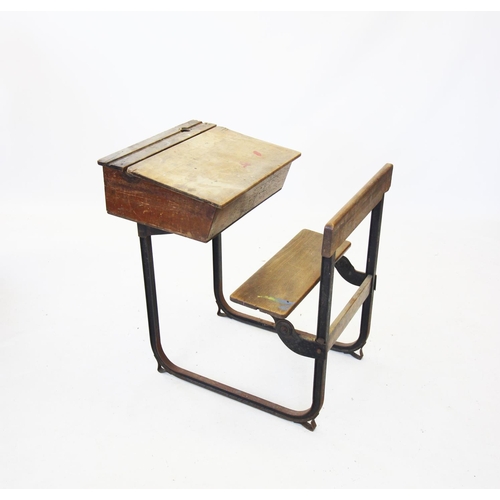 725 - An early 20th century ash and beech school desk and bench combined, raised upon a pair of cast iron ... 