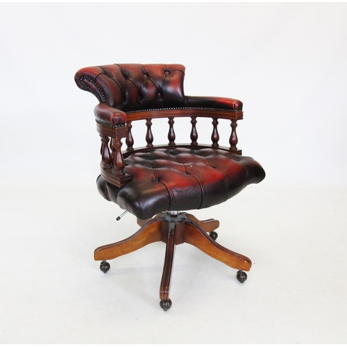 733 - An oxblood red leather revolving desk chair, late 20th century, with button back seat and padded arm... 