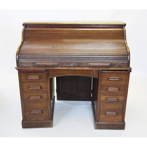 723 - An early 20th century oak roll top desk, the 'S' shaped tambour front enclosing a compartmentalised ... 