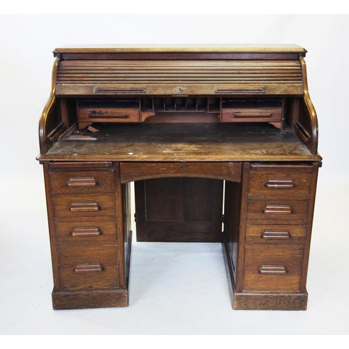 723 - An early 20th century oak roll top desk, the 'S' shaped tambour front enclosing a compartmentalised ... 