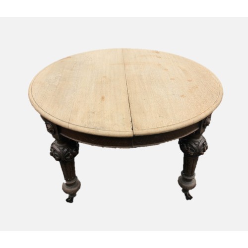 676 - A Victorian oak scrub top extending dining table, the circular moulded top raised upon leaf carved a... 