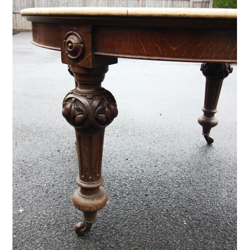 676 - A Victorian oak scrub top extending dining table, the circular moulded top raised upon leaf carved a... 