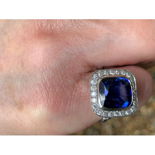 123 - A sapphire and diamond ring, the central cushion mixed cut sapphire with a border surround of twenty... 