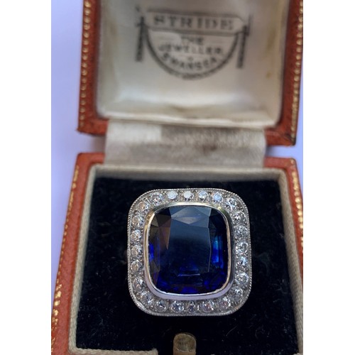 123 - A sapphire and diamond ring, the central cushion mixed cut sapphire with a border surround of twenty... 