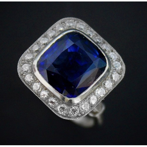 123 - A sapphire and diamond ring, the central cushion mixed cut sapphire with a border surround of twenty... 