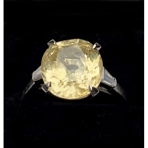 122 - A yellow sapphire and diamond ring, the central cushion mixed cut sapphire claw set with a baguette ... 