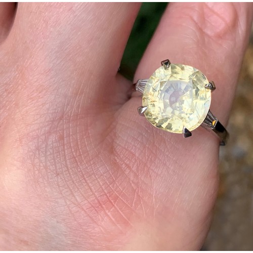 122 - A yellow sapphire and diamond ring, the central cushion mixed cut sapphire claw set with a baguette ... 