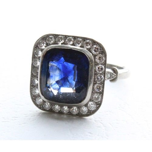 123 - A sapphire and diamond ring, the central cushion mixed cut sapphire with a border surround of twenty... 