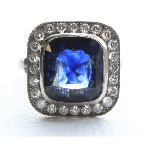 123 - A sapphire and diamond ring, the central cushion mixed cut sapphire with a border surround of twenty... 