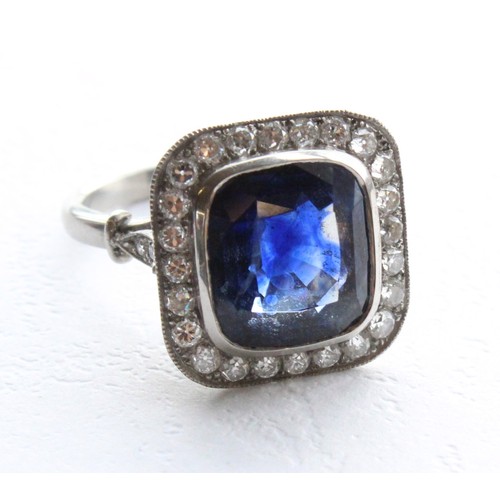 123 - A sapphire and diamond ring, the central cushion mixed cut sapphire with a border surround of twenty... 