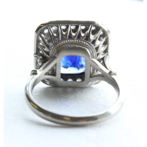 123 - A sapphire and diamond ring, the central cushion mixed cut sapphire with a border surround of twenty... 