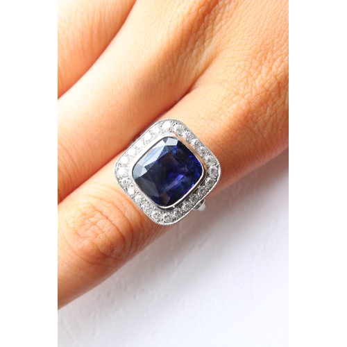 123 - A sapphire and diamond ring, the central cushion mixed cut sapphire with a border surround of twenty... 