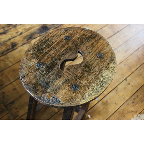 727 - An early 20th century oak clerks stool, the oval seat with an 'S' shaped aperture, raised upon chamf... 