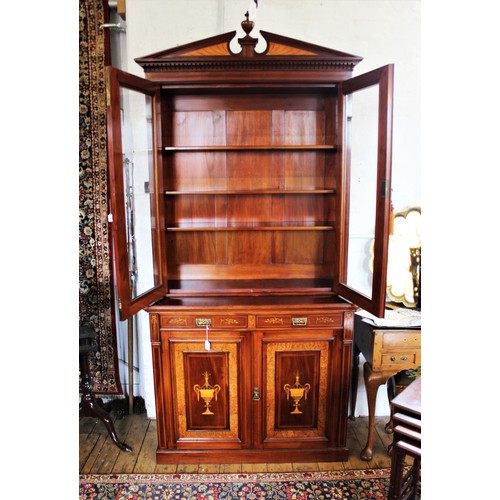 704 - An Edwardian Sheraton revival mahogany library bookcase, the architectural pediment inlaid with sati... 