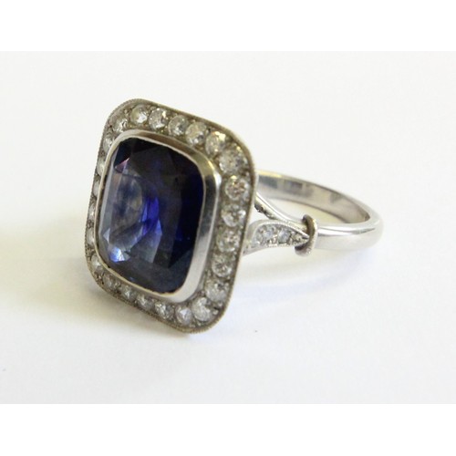 123 - A sapphire and diamond ring, the central cushion mixed cut sapphire with a border surround of twenty... 