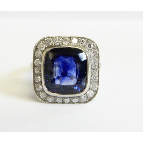 123 - A sapphire and diamond ring, the central cushion mixed cut sapphire with a border surround of twenty... 