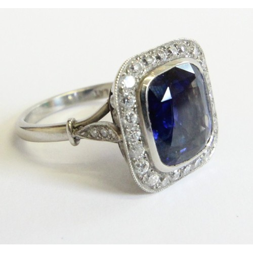 123 - A sapphire and diamond ring, the central cushion mixed cut sapphire with a border surround of twenty... 