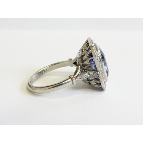 123 - A sapphire and diamond ring, the central cushion mixed cut sapphire with a border surround of twenty... 