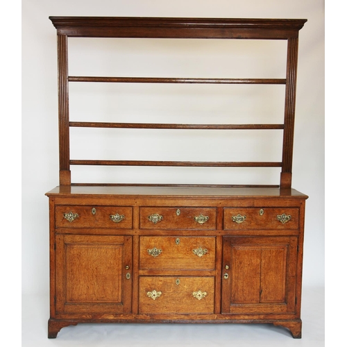 825 - A George III oak Welsh dresser, the open plate rack with a moulded cornice above three shelves, upon... 