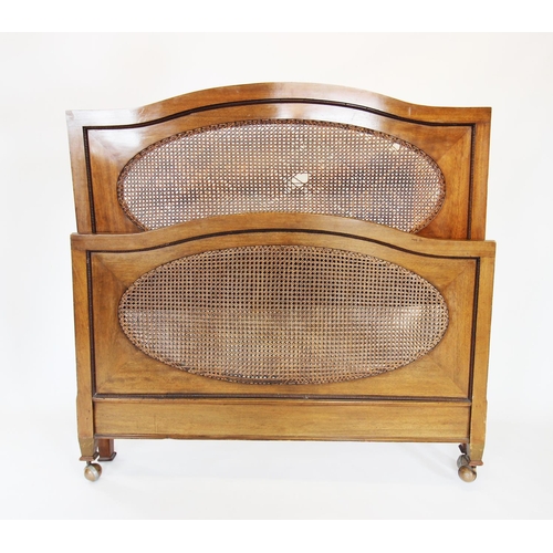 892 - An early 20th century mahogany and rattan bedstead, the arched head and foot board inset with an ova... 