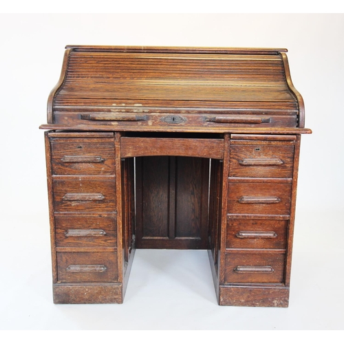 902 - An early 20th century oak roll top desk, the 'S' form tambour front enclosing a compartmentalised in... 