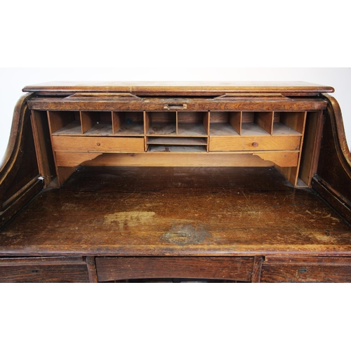 902 - An early 20th century oak roll top desk, the 'S' form tambour front enclosing a compartmentalised in... 