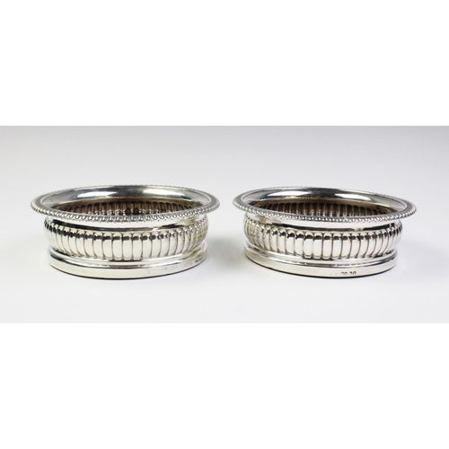 11 - A pair of George IV silver bottle coasters, London 1826, each of circular form with fluted sides and... 