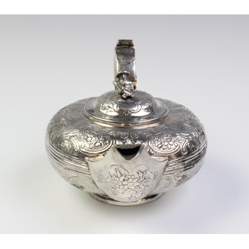 18 - A Victorian white metal teapot, of squashed ovoid form with scroll capped handle on circular spreadi... 