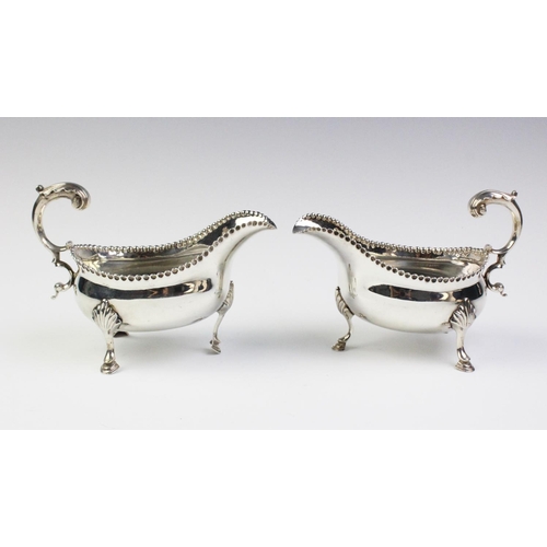21 - A pair of George III silver sauce boats, each of oval form with leaf-capped scroll handle, punch bea... 