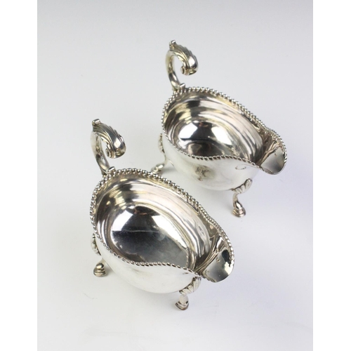 21 - A pair of George III silver sauce boats, each of oval form with leaf-capped scroll handle, punch bea... 