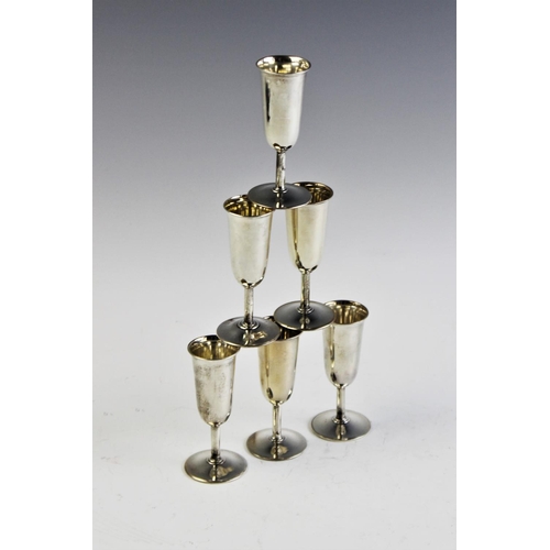 64 - A set of six silver tots, each of tapering cylindrical form on circular spreading foot, 8cm high, gr... 