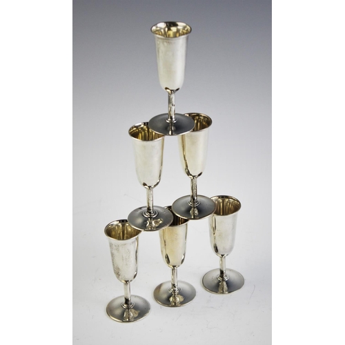 64 - A set of six silver tots, each of tapering cylindrical form on circular spreading foot, 8cm high, gr... 