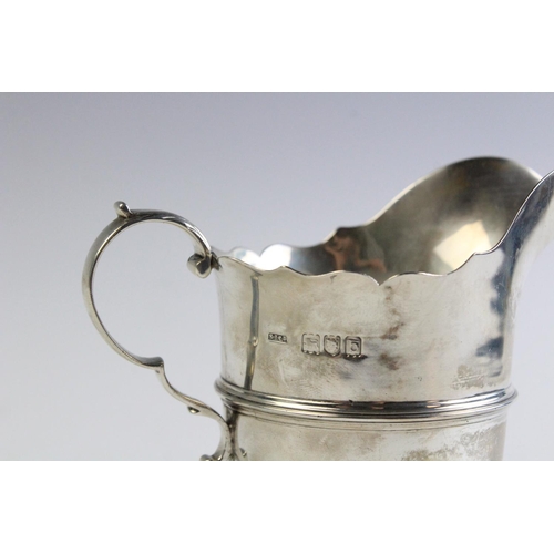33 - A Victorian silver cream jug by Stokes & Ireland, London 1897, with shaped rim and scrolling handle ... 