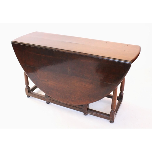 690 - An 18th century oak drop leaf dining table, the oval top above a single frieze drawer, raised upon r... 