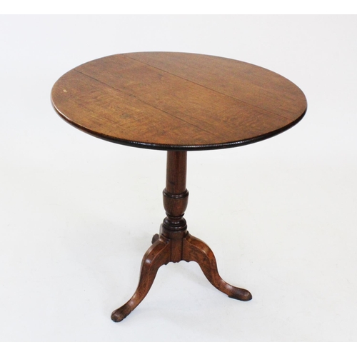 697 - A George III oak tripod table, the circular top raised upon a ring turned tapering column and three ... 