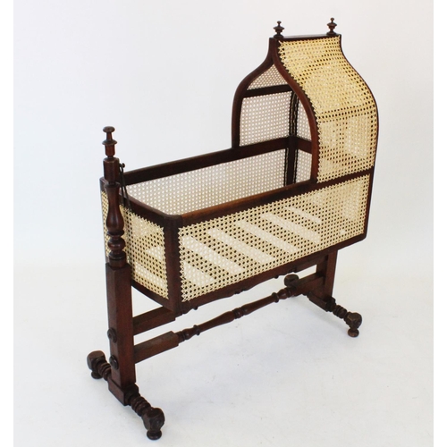 748 - A Victorian mahogany and rattan cradle, with turned finials upon an onion shaped rattan canopy and r... 