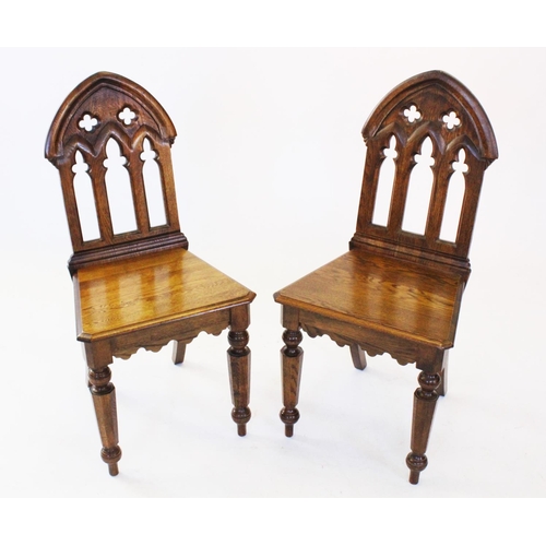 753 - A pair of Puginesque oak hall chairs, late 20th century, each with a Gothic influence open work back... 