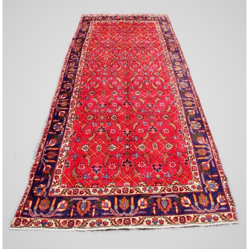 669 - A large red ground Persian Tabriz runner, with all over design and vibrant blue border, 381cm x 145c... 