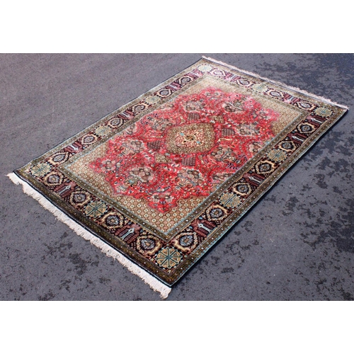 664 - A Persian pattern silkwork rug, the central green medallion on a red ground enclosed by foliate urns... 