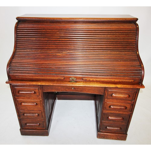 796 - An early 20th century oak roll top desk, the 'S' shaped tambour front enclosing a compartmentalised ... 