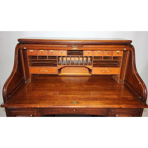 796 - An early 20th century oak roll top desk, the 'S' shaped tambour front enclosing a compartmentalised ... 