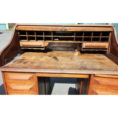 811 - An oak early 20th century oak roll top desk, the 'S' shaped tambour front enclosing a compartmentali... 